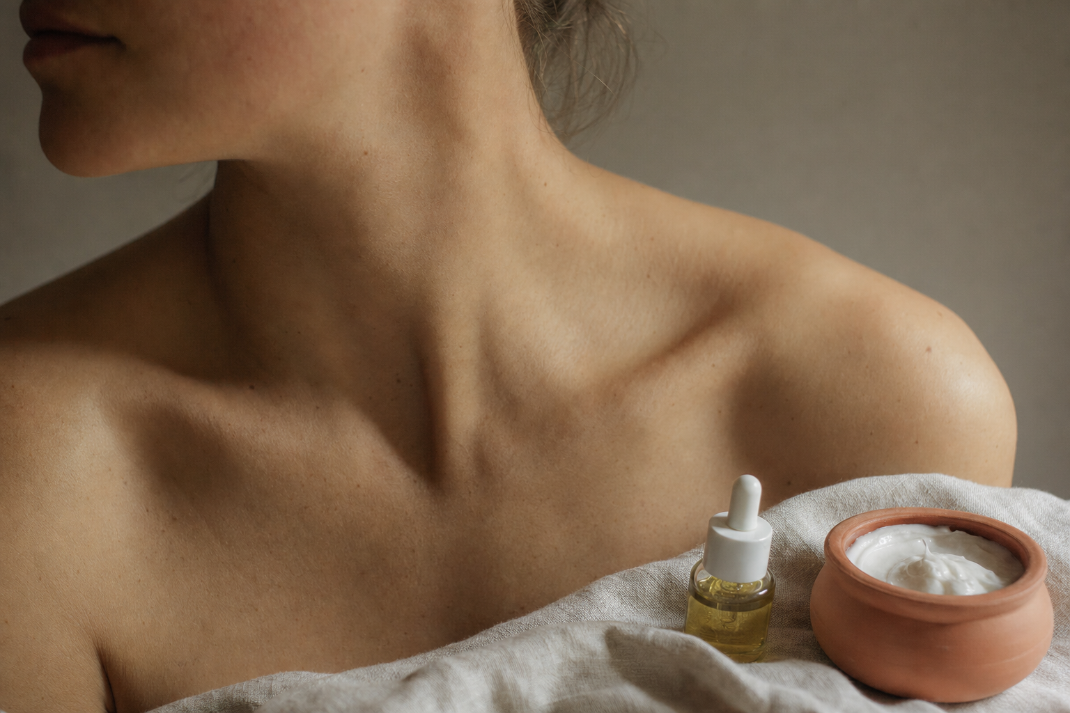 Close-up of bare skin with skincare bottles nearby in soft natural light, illustrating barrier health