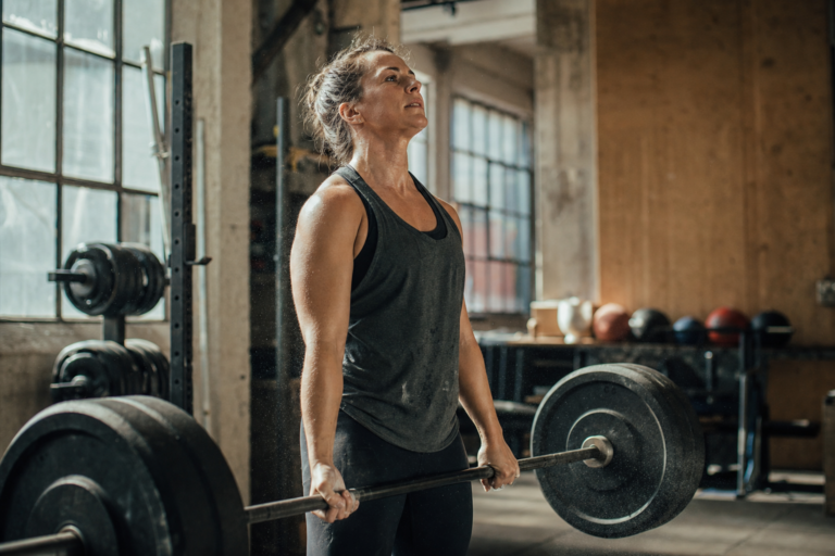 Person performing a barbell lift in a sunlit gym, illustrating strength training as metabolic health